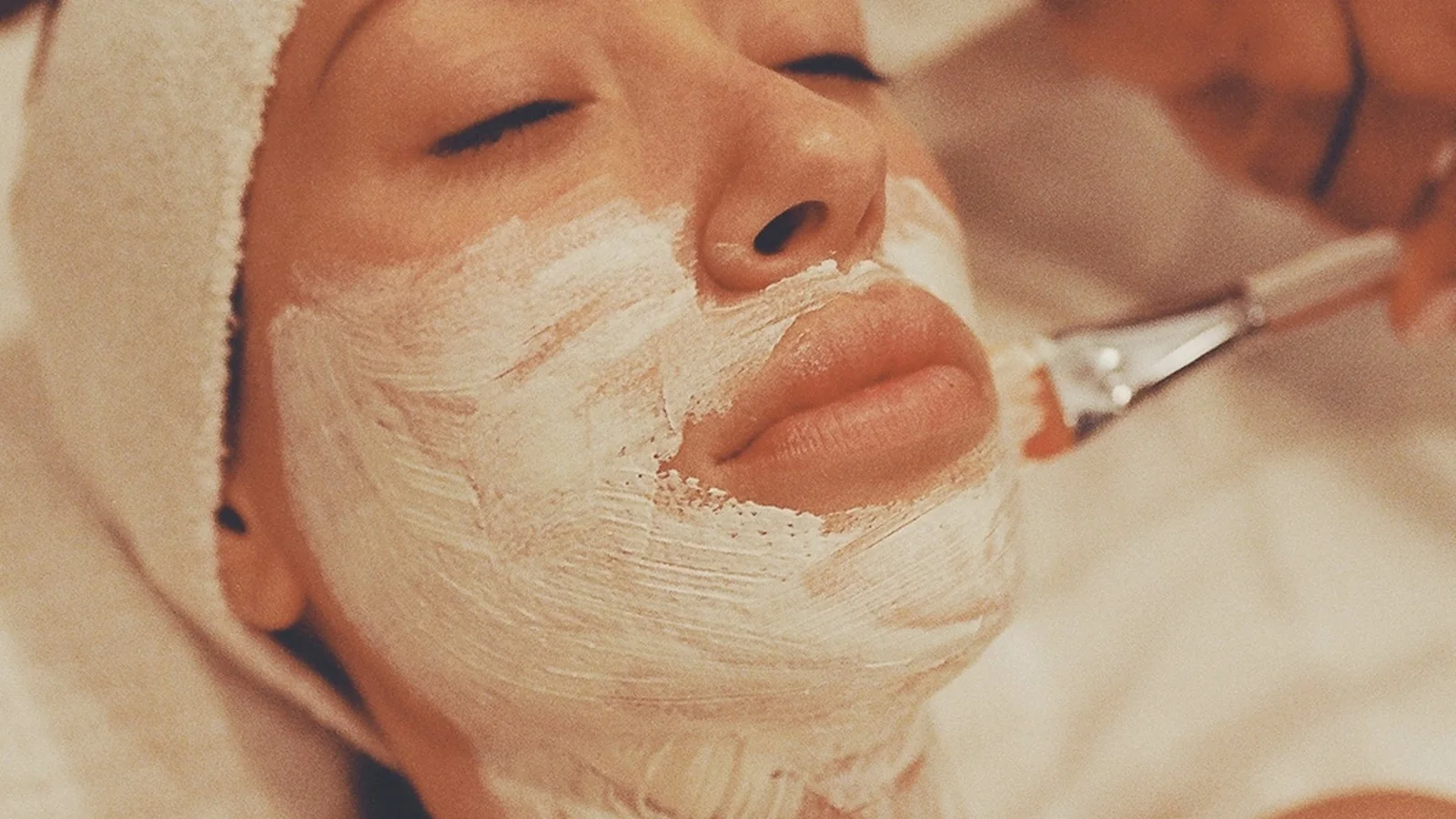 A soft facial mask being applied with a brush during calming skin care.